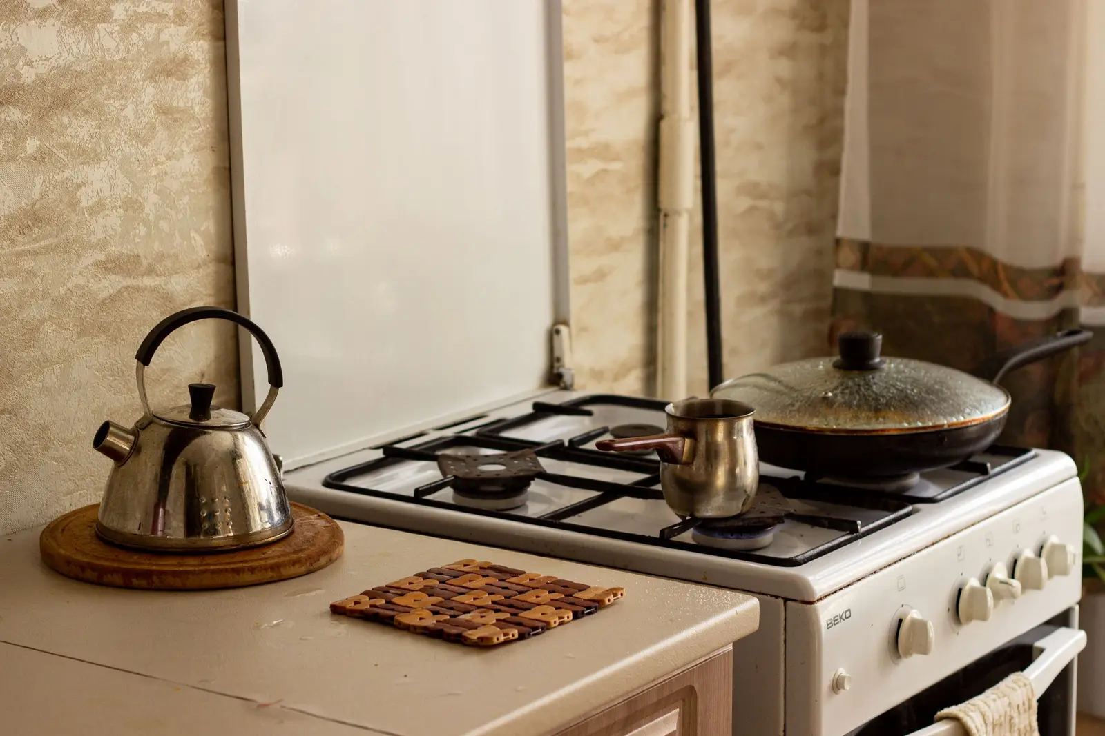 Bouilloire posée sur un dessous de plat, à côté de la plaque de cuisson
