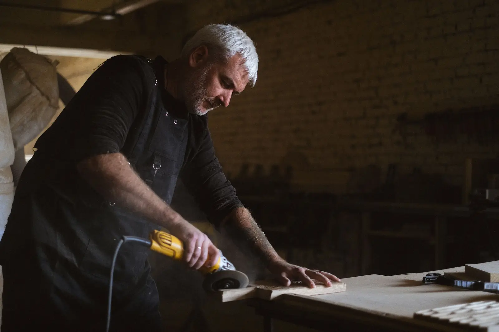 Artisan travaillant une plaque de pierre à la meuleuse, en atelier