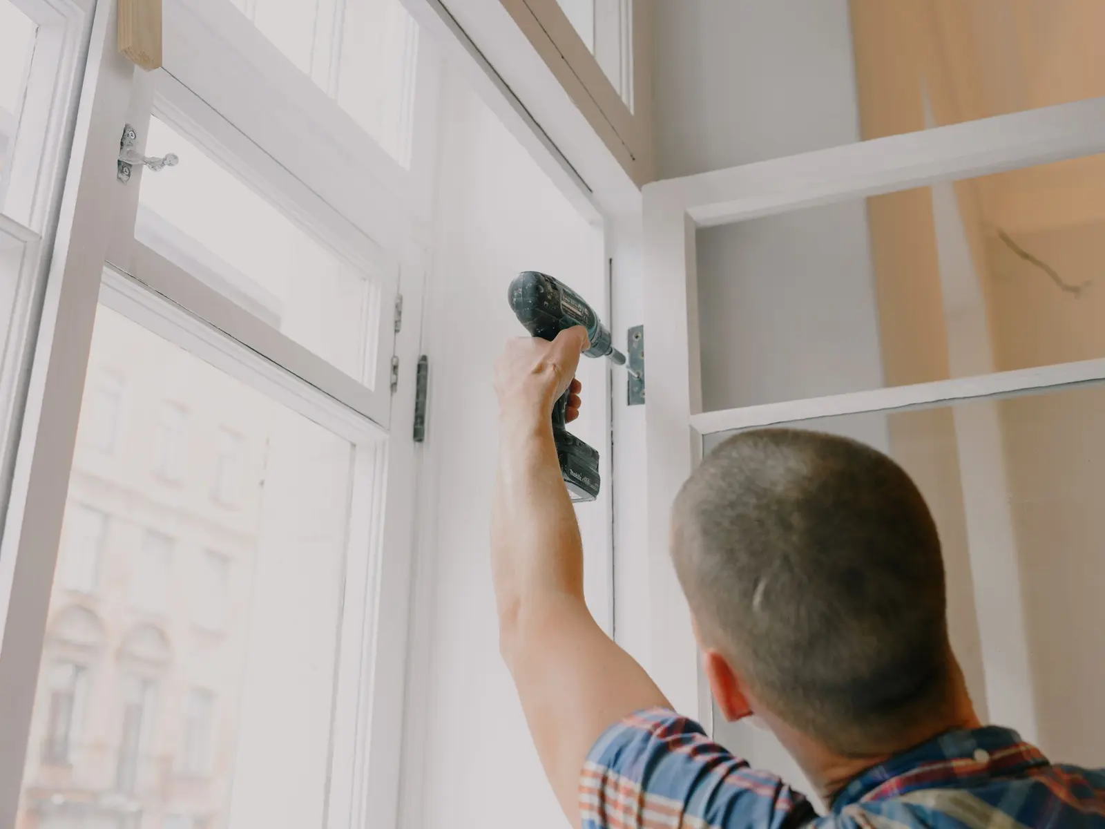 Poseur fixant une porte de meuble à la visseuse