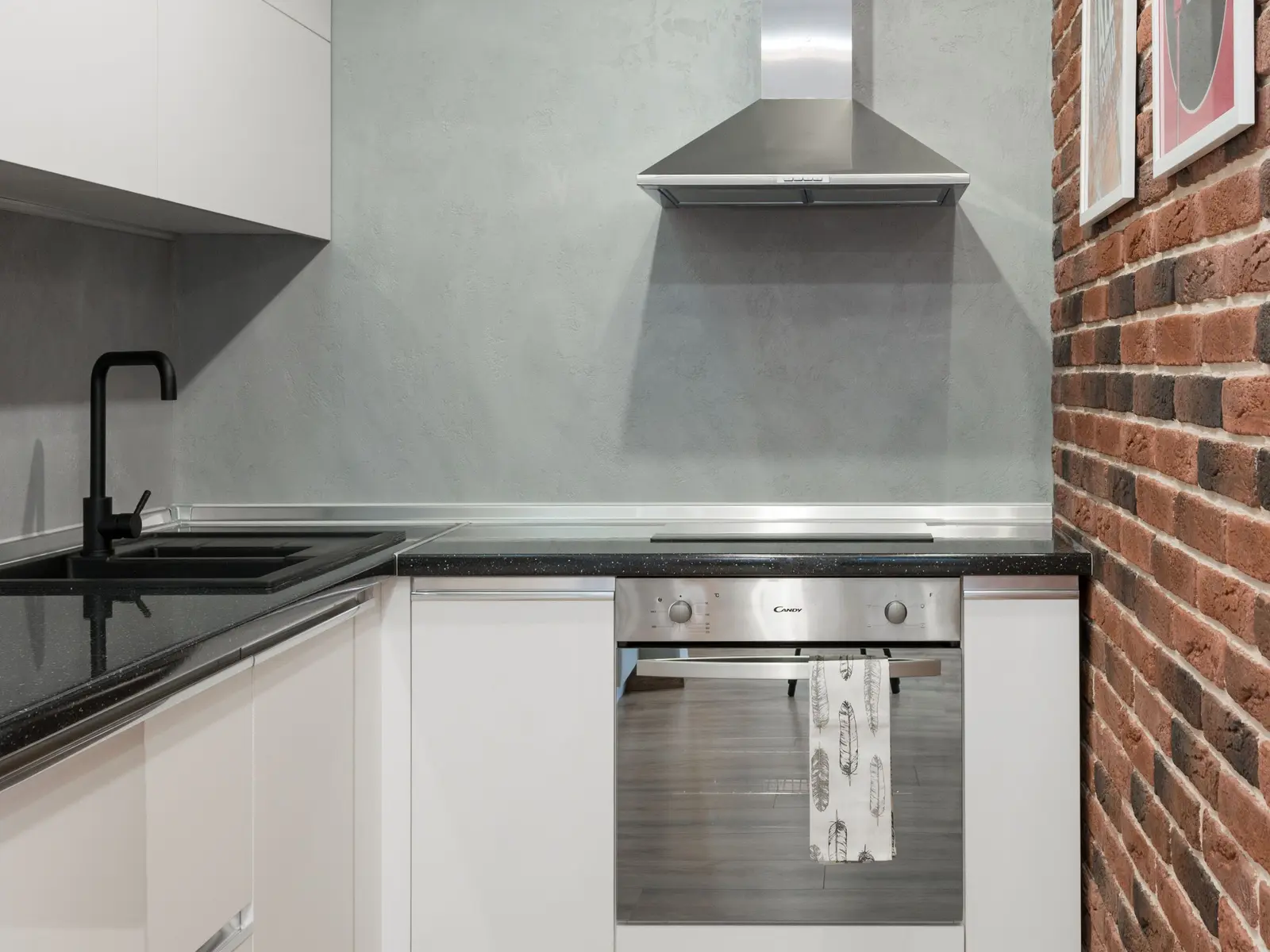 Hotte cheminée en inox au-dessus d'une table de cuisson dans une cuisine d'appartement