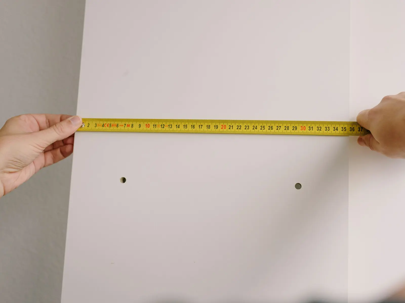 Mètre ruban tendu contre un mur blanc