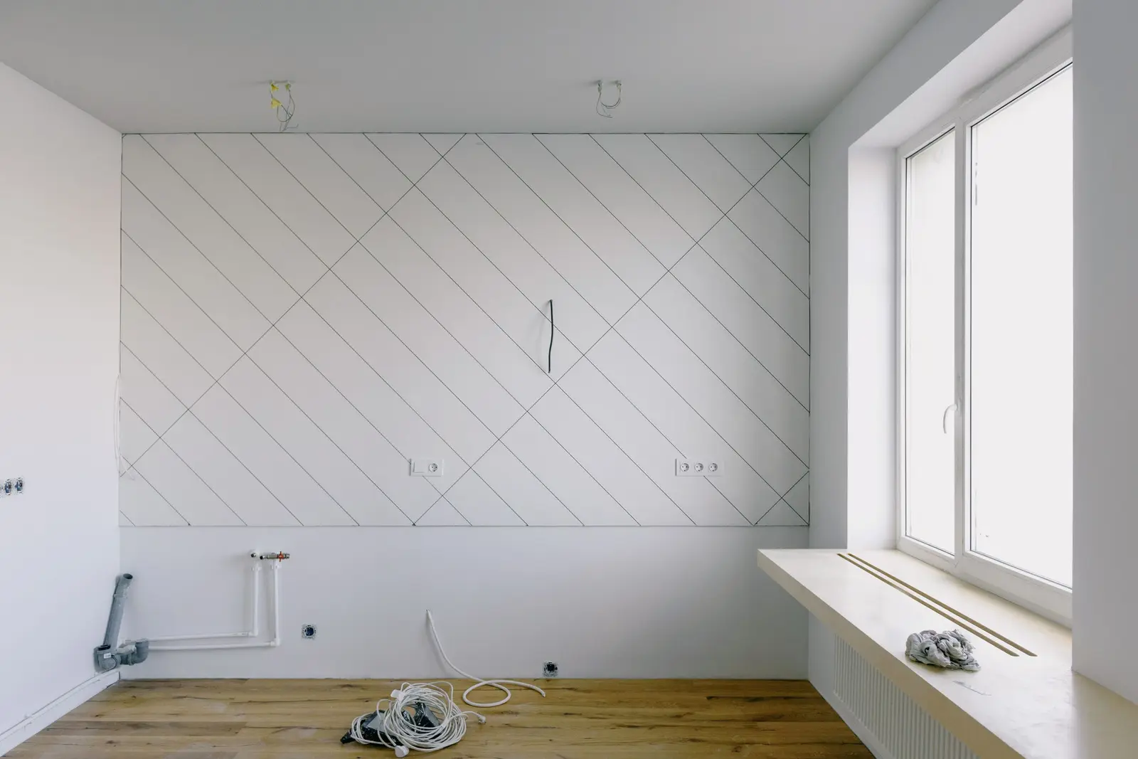 Arrivées d'eau, évacuation et prises sur un mur de cuisine avant la pose des meubles