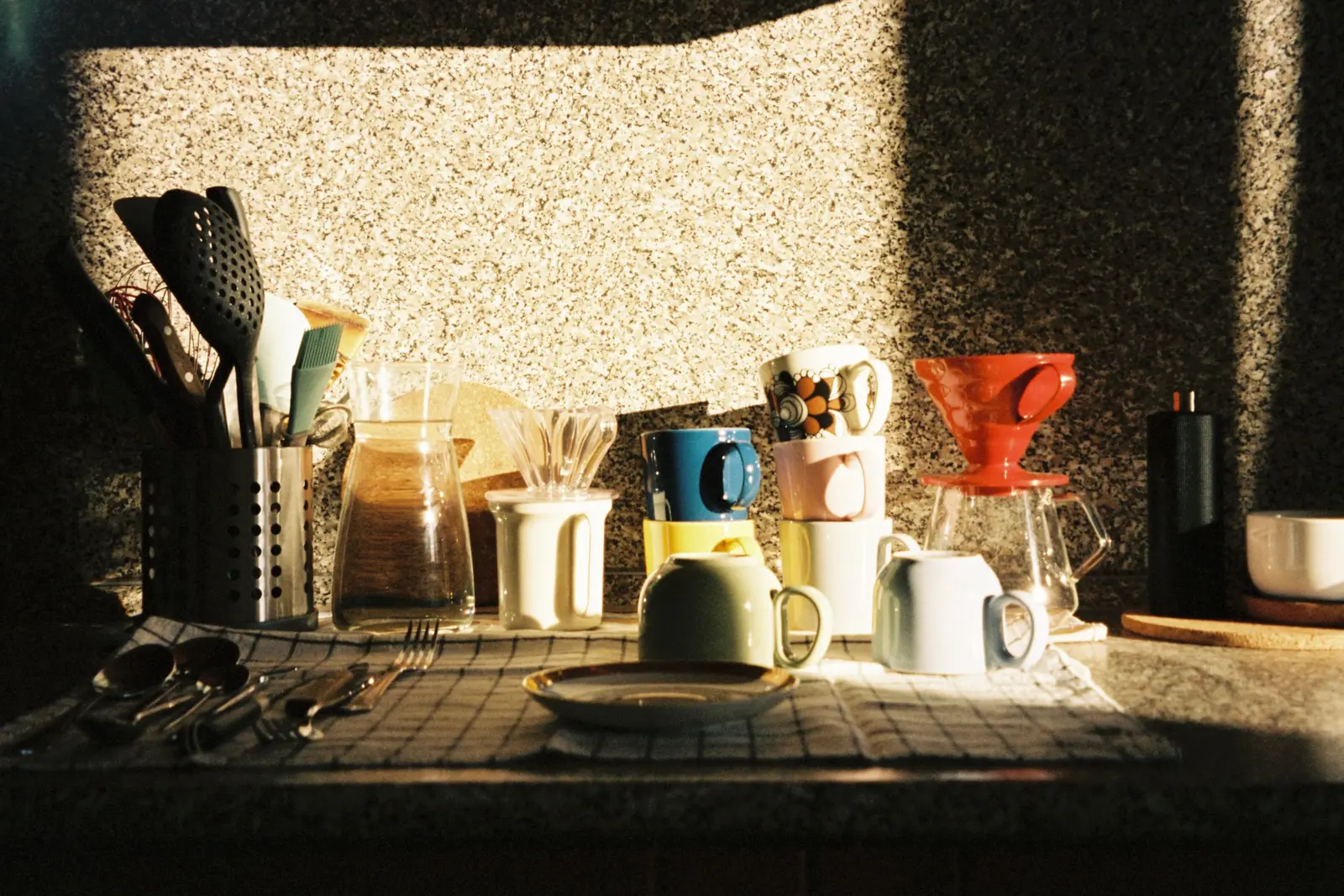 Ustensiles et tasses sur un plan de travail en pleine lumière