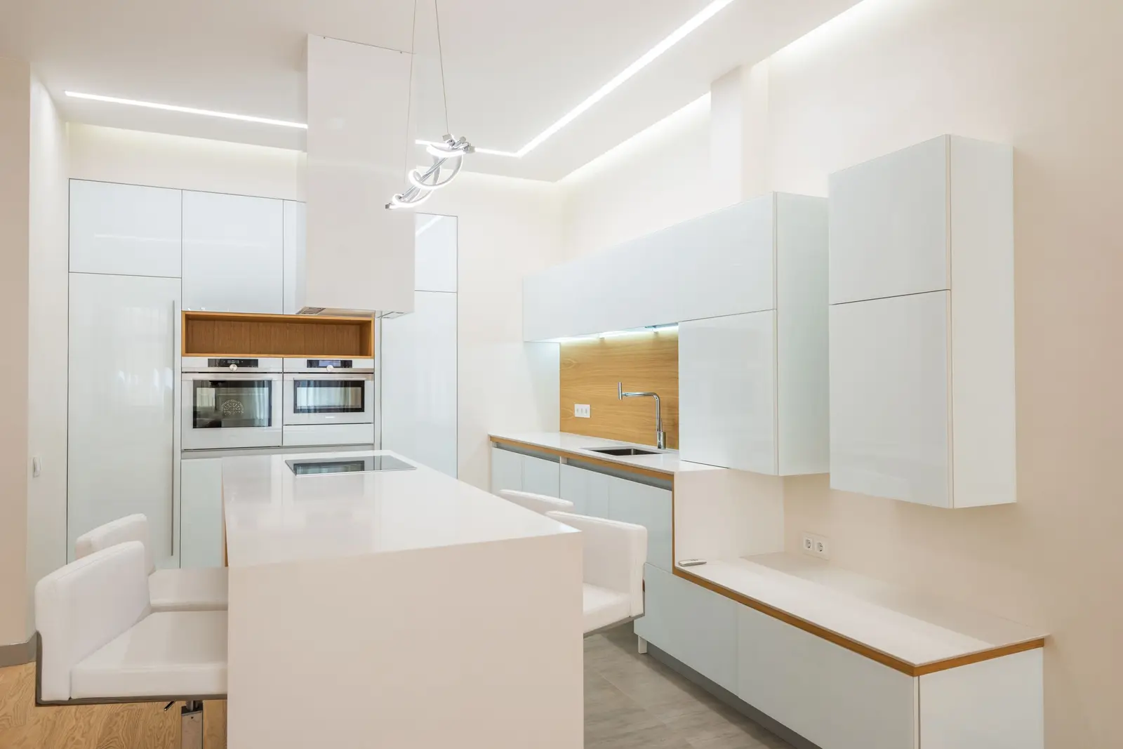 Cuisine blanche sans poignée éclairée par des rubans lumineux sous les meubles hauts