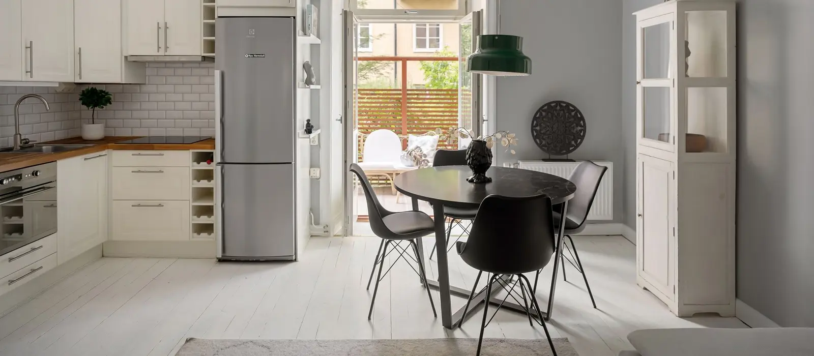 Cuisine et coin repas d'un appartement, porte vitrée ouverte sur une cour