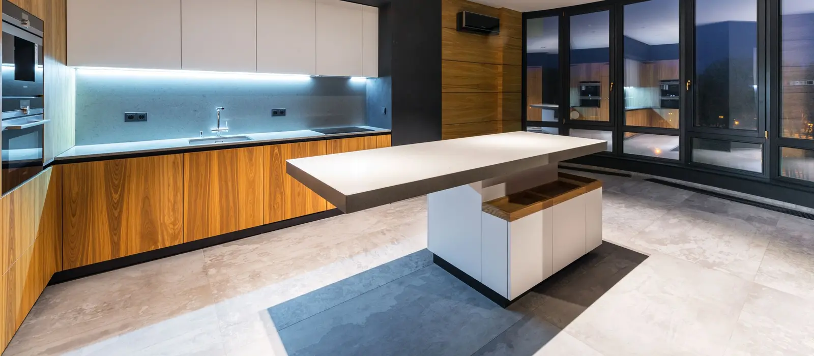 Cuisine contemporaine en bois et blanc, îlot en porte-à-faux face à de grandes baies vitrées