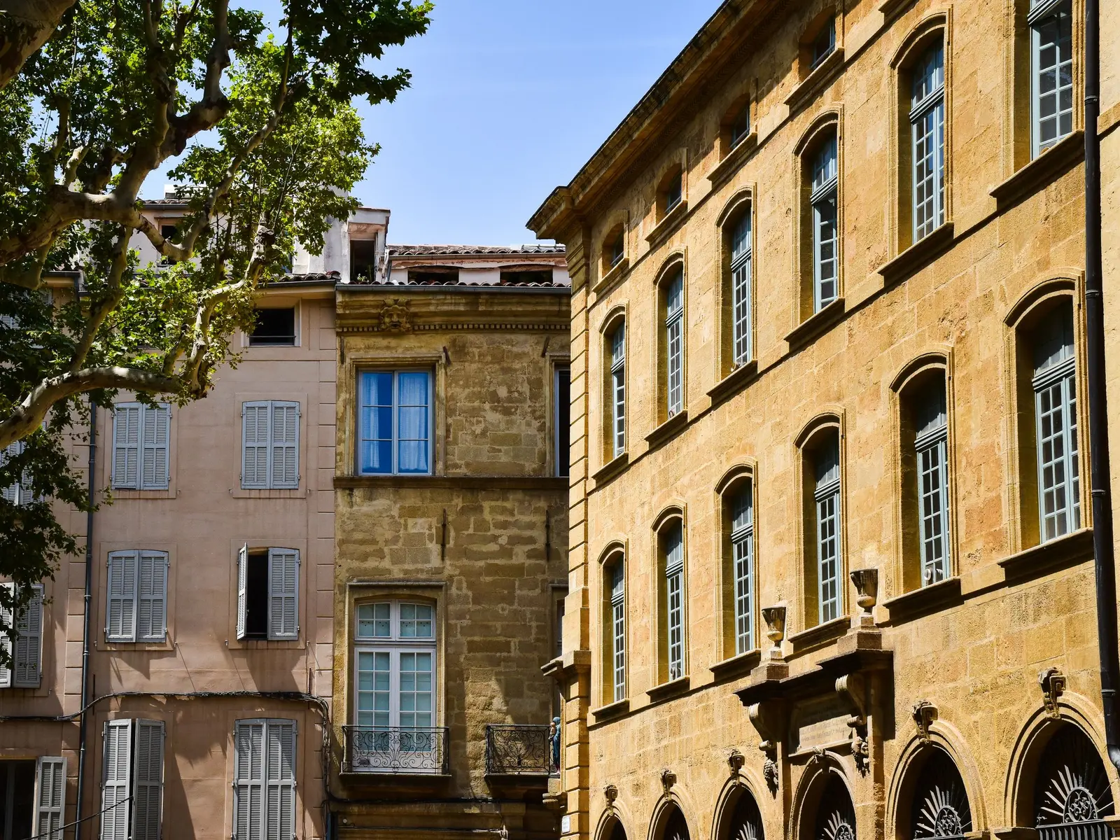 Façades en pierre blonde et fenêtres à volets dans une rue du centre ancien d'Aix-en-Provence
